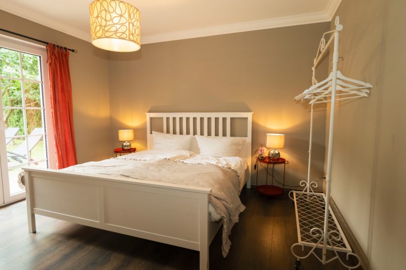 Schlafzimmer mit Doppelbett und hängendem Rattansessel